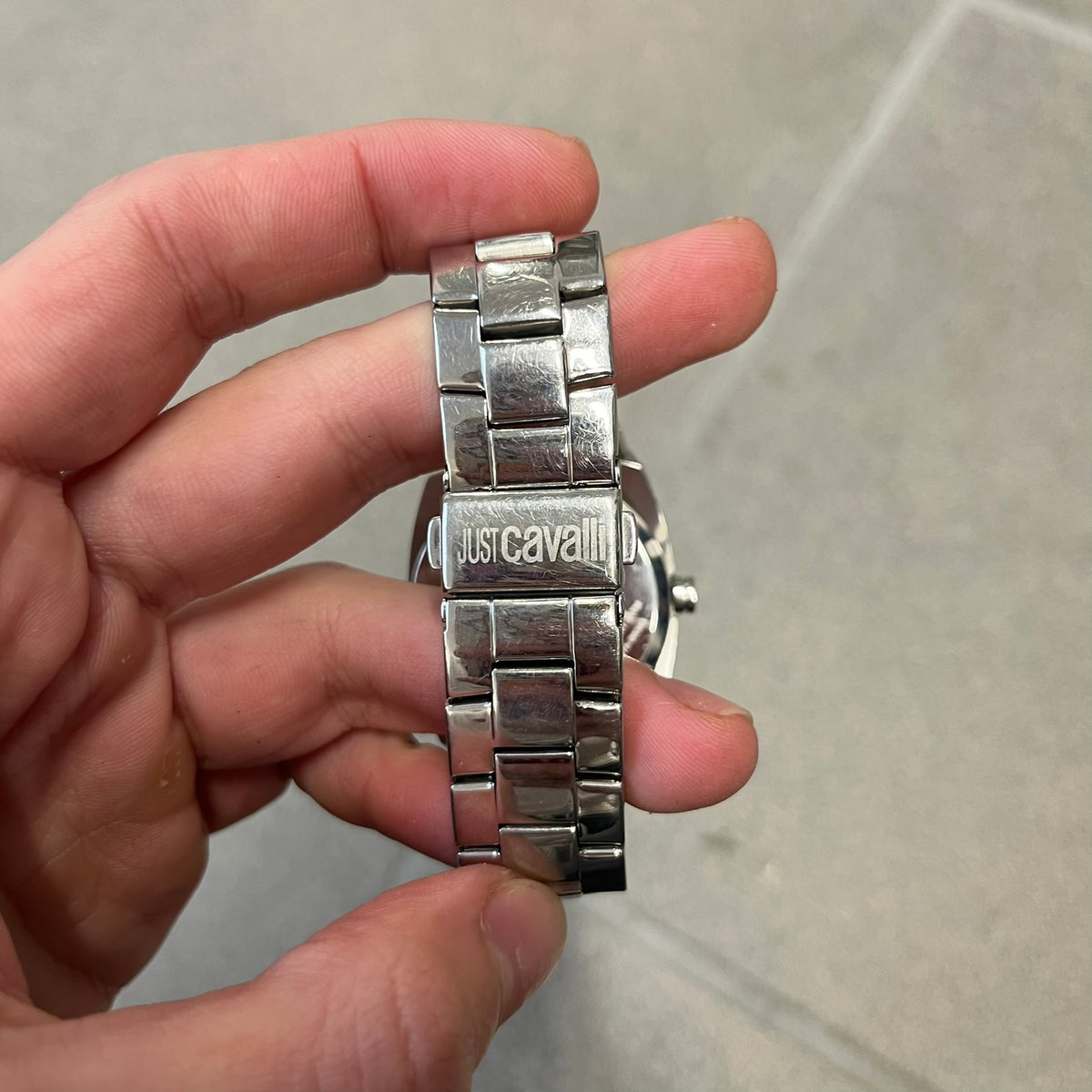 Just Cavalli 2010’s Pink Dial Analog Watch is a stainless steel watch with a raised oval case and an oval pink dial with a large silver Just Cavalli logo. The clasp is Just Cavalli branded, and the watch comes with its box and papers.