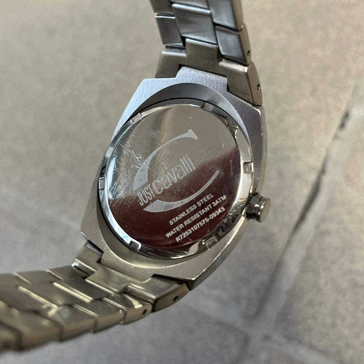 Just Cavalli 2010’s Pink Dial Analog Watch is a stainless steel watch with a raised oval case and an oval pink dial with a large silver Just Cavalli logo. The clasp is Just Cavalli branded, and the watch comes with its box and papers.