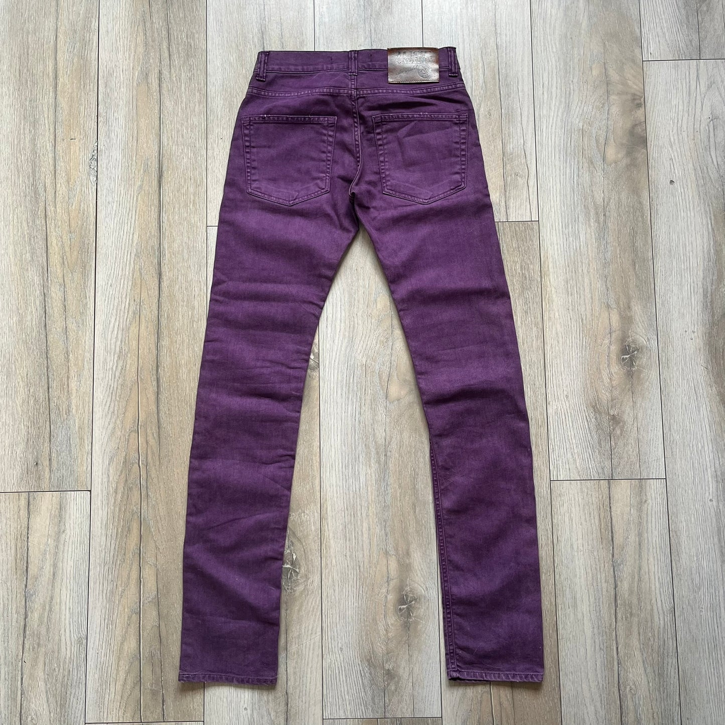 Just Cavalli 2010s Purple Slim Jeans are slim-fit denim jeans finished in a full purple colorway. The pair features classic front and back pocket construction, branded metal button closure, and small metal stud details on the pockets. Additional details include a rear leather Just Cavalli logo patch, interior Just Cavalli tag, and original paper tag.
