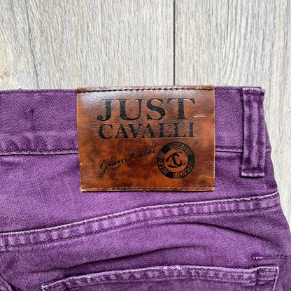 Just Cavalli 2010s Purple Slim Jeans are slim-fit denim jeans finished in a full purple colorway. The pair features classic front and back pocket construction, branded metal button closure, and small metal stud details on the pockets. Additional details include a rear leather Just Cavalli logo patch, interior Just Cavalli tag, and original paper tag.