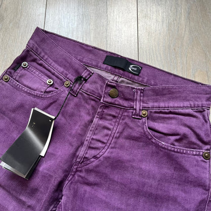 Just Cavalli 2010s Purple Slim Jeans are slim-fit denim jeans finished in a full purple colorway. The pair features classic front and back pocket construction, branded metal button closure, and small metal stud details on the pockets. Additional details include a rear leather Just Cavalli logo patch, interior Just Cavalli tag, and original paper tag.