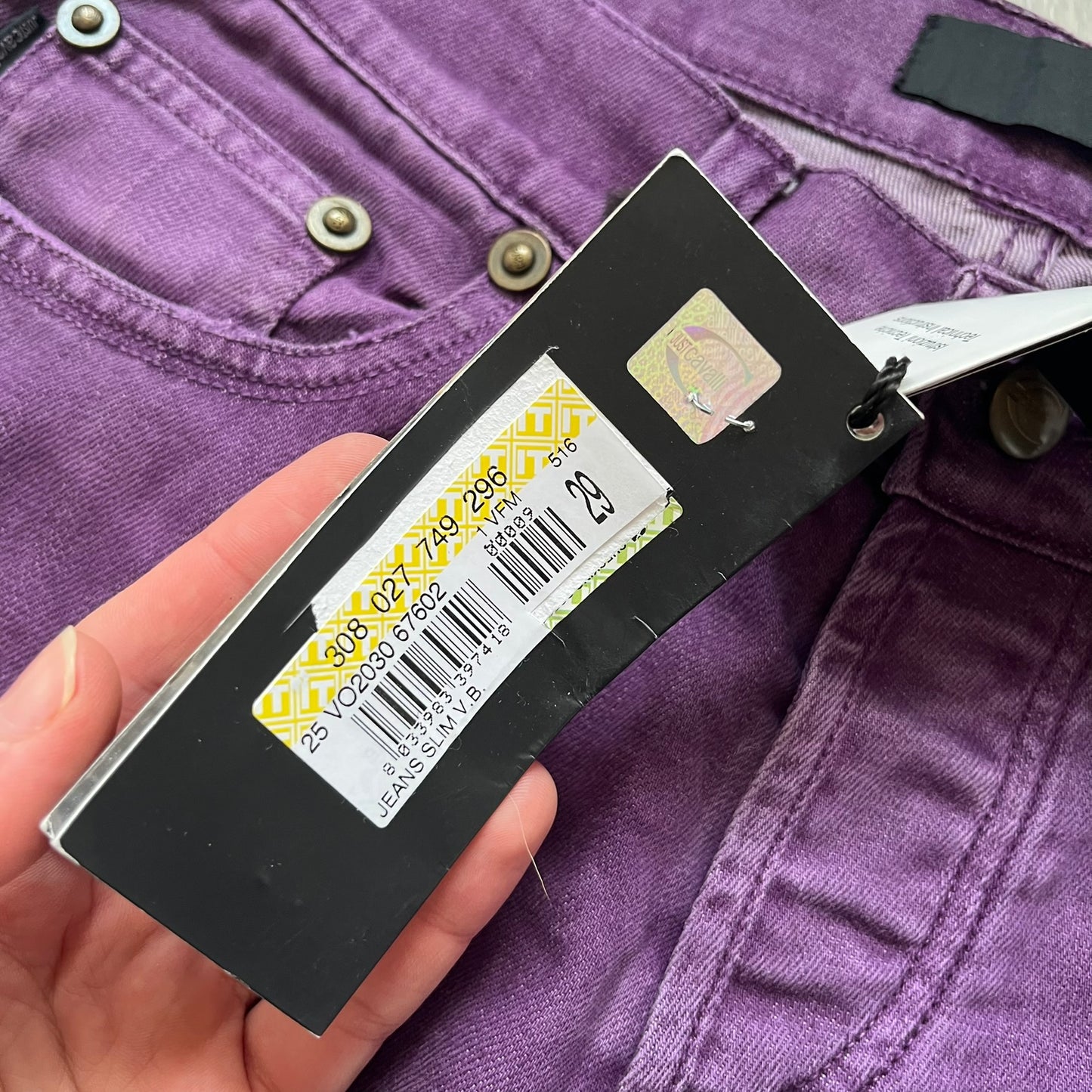 Just Cavalli 2010s Purple Slim Jeans are slim-fit denim jeans finished in a full purple colorway. The pair features classic front and back pocket construction, branded metal button closure, and small metal stud details on the pockets. Additional details include a rear leather Just Cavalli logo patch, interior Just Cavalli tag, and original paper tag.