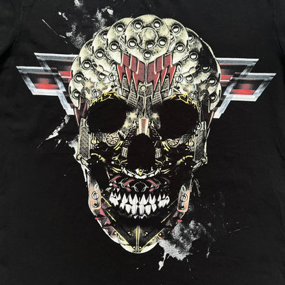 Just Cavalli AW2016 Metal Skull Print Black Tee is a black cotton T-shirt featuring a detailed front graphic of a metallic-style skull composed of gold, silver, and red plate-like elements. The design includes red accents and white splatter effects in the background for contrast. It comes with a black Just Cavalli neck tag and a small side tag.