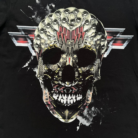 Just Cavalli AW2016 Metal Skull Print Black Tee is a black cotton T-shirt featuring a detailed front graphic of a metallic-style skull composed of gold, silver, and red plate-like elements. The design includes red accents and white splatter effects in the background for contrast. It comes with a black Just Cavalli neck tag and a small side tag.