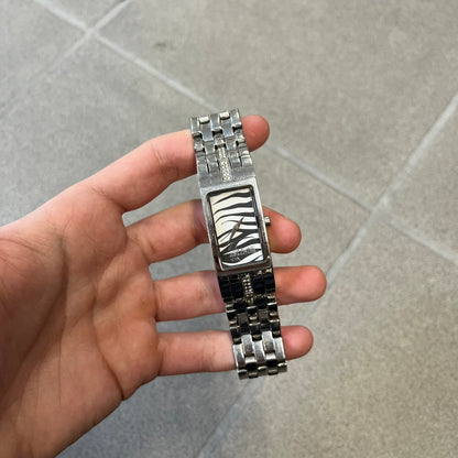Just Cavalli Colas 2010’s Zebra Analog Watch is a stainless steel analog watch with a white and black zebra print dial and a silver Just Cavalli logo. The band matches the width of the case and has crystal details, and “Cavalli” is engraved on one side of the case.