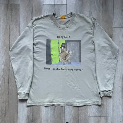 Longsleeve tee from the FW18 Kanye West x Pornhub collection, released 09/07/2018. Vapor color, featuring a front illustration of Riley Reid with her name above and “Top Female Performer” below. Back has the numbers “6918” (futuristic theme set in the year 6918). Includes printed Pornhub tag and YEEZY wash tag, part of a limited run commemorating the 2018 Pornhub Awards.