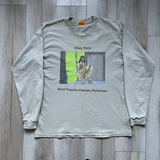 Longsleeve tee from the FW18 Kanye West x Pornhub collection, released 09/07/2018. Vapor color, featuring a front illustration of Riley Reid with her name above and “Top Female Performer” below. Back has the numbers “6918” (futuristic theme set in the year 6918). Includes printed Pornhub tag and YEEZY wash tag, part of a limited run commemorating the 2018 Pornhub Awards.