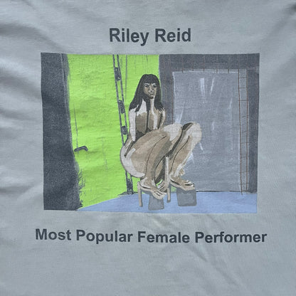 Longsleeve tee from the FW18 Kanye West x Pornhub collection, released 09/07/2018. Vapor color, featuring a front illustration of Riley Reid with her name above and “Top Female Performer” below. Back has the numbers “6918” (futuristic theme set in the year 6918). Includes printed Pornhub tag and YEEZY wash tag, part of a limited run commemorating the 2018 Pornhub Awards.