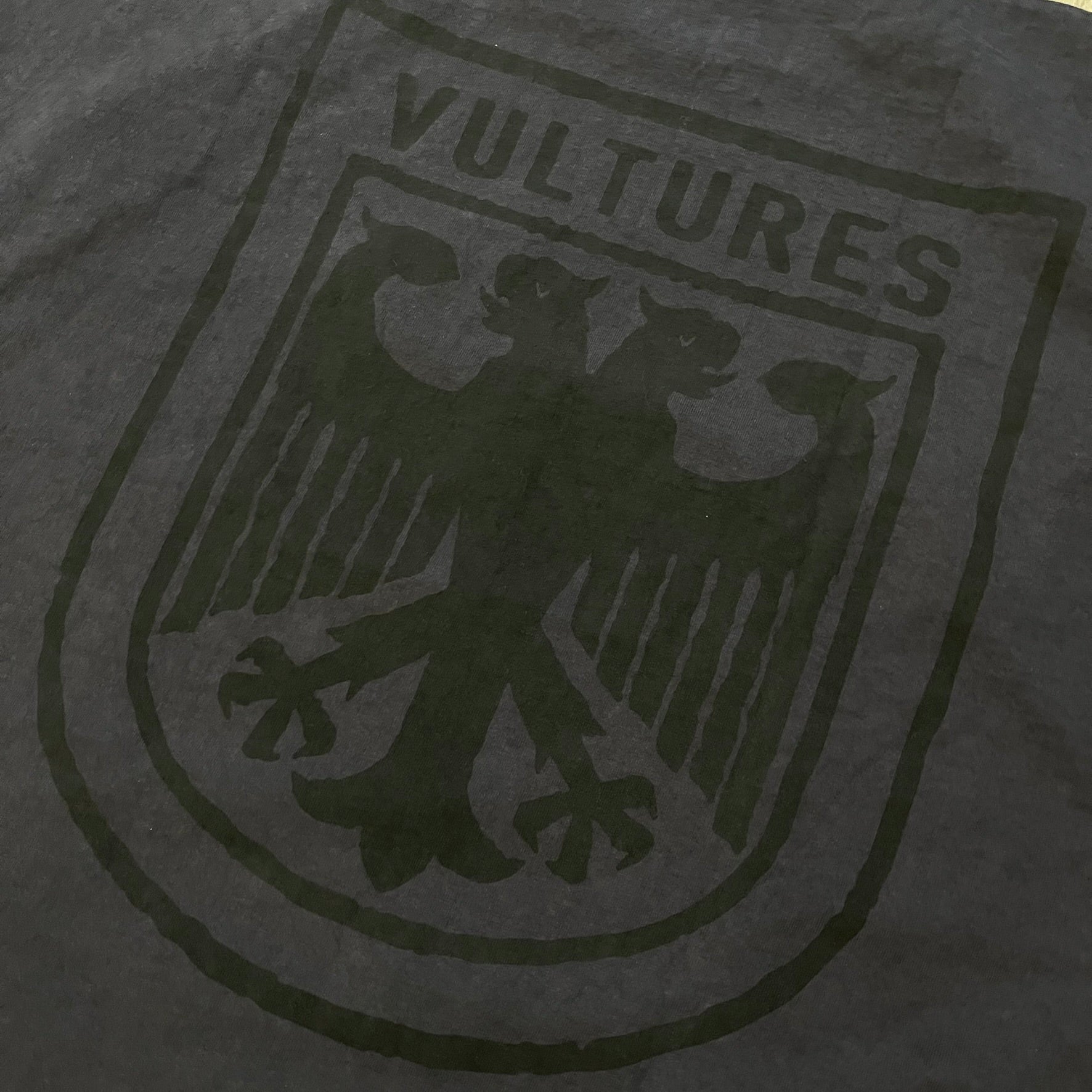 Kanye West Vultures Box Tee in navy features a large Vultures Eagles logo on the back and a smaller matching logo on the chest. Designed with an oversized, boxy silhouette, this T-shirt offers a relaxed fit. Made from high-quality, durable materials, it provides comfort for everyday wear while showcasing Yeezy’s distinctive style.