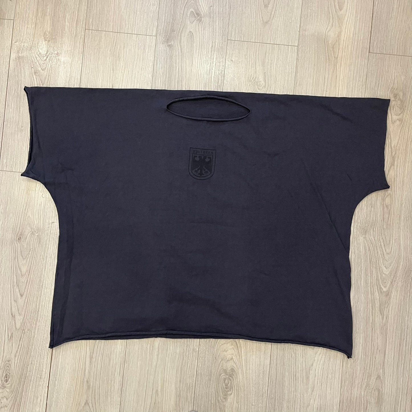 Kanye West Vultures Box Tee in navy features a large Vultures Eagles logo on the back and a smaller matching logo on the chest. Designed with an oversized, boxy silhouette, this T-shirt offers a relaxed fit. Made from high-quality, durable materials, it provides comfort for everyday wear while showcasing Yeezy’s distinctive style.