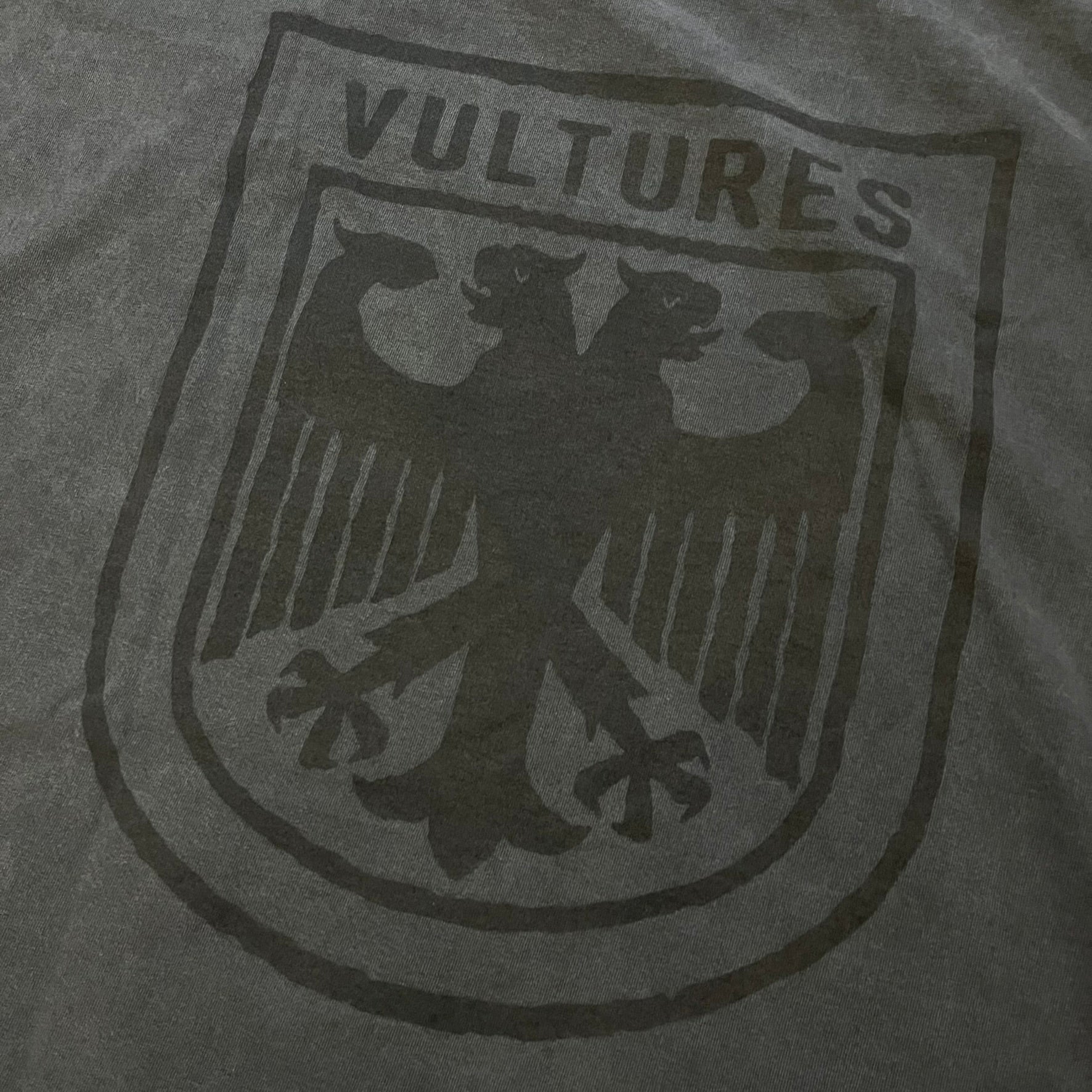 Kanye West Vultures Box Tee in washed black features a large Vultures Eagles logo on the back and a smaller matching logo on the chest. Designed with an oversized, boxy silhouette, this T-shirt offers a relaxed fit. Made from high-quality, durable materials, it provides comfort for everyday wear while showcasing Yeezy’s distinctive style.