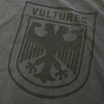 Kanye West Vultures Box Tee in washed black features a large Vultures Eagles logo on the back and a smaller matching logo on the chest. Designed with an oversized, boxy silhouette, this T-shirt offers a relaxed fit. Made from high-quality, durable materials, it provides comfort for everyday wear while showcasing Yeezy’s distinctive style.
