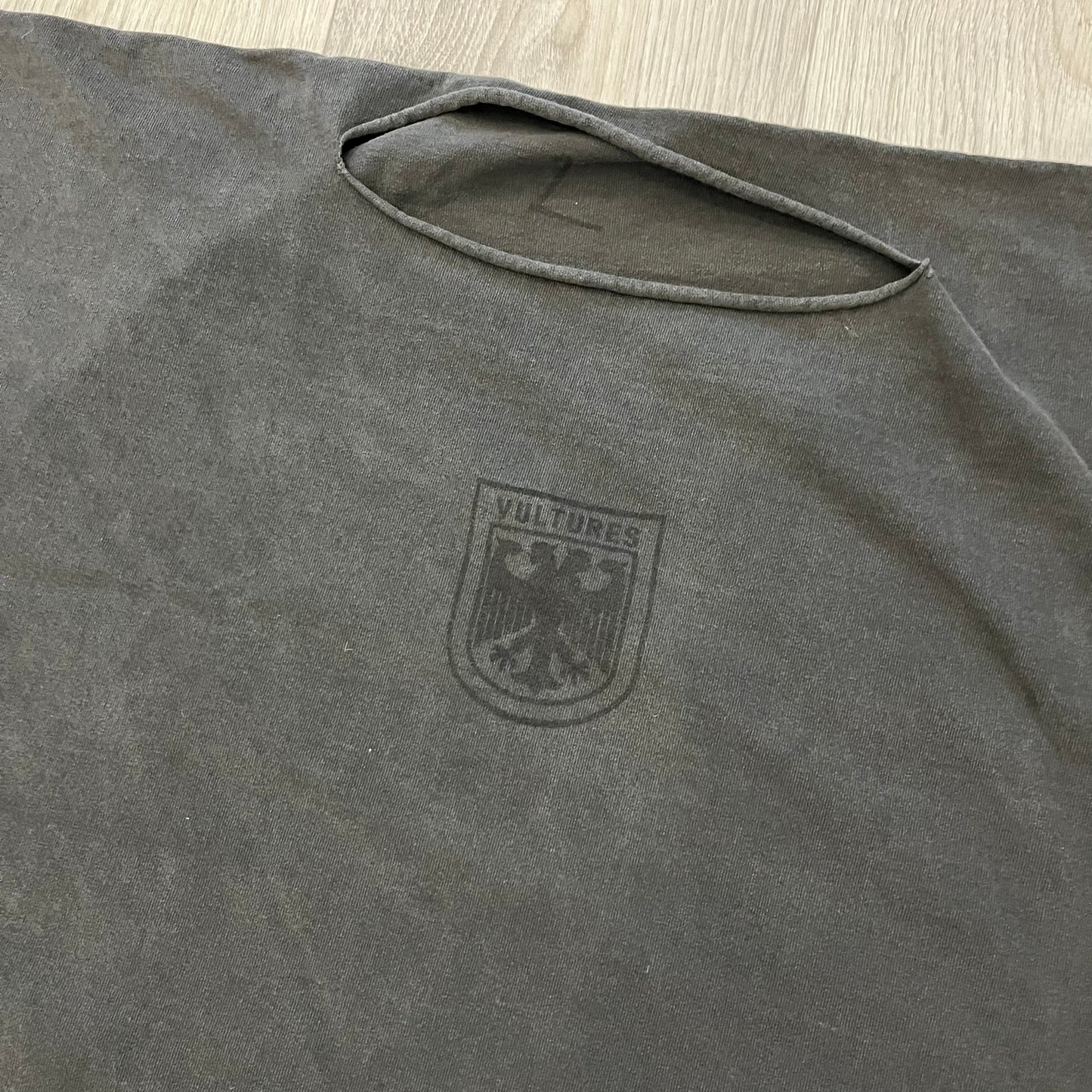 Kanye West Vultures Box Tee in washed black features a large Vultures Eagles logo on the back and a smaller matching logo on the chest. Designed with an oversized, boxy silhouette, this T-shirt offers a relaxed fit. Made from high-quality, durable materials, it provides comfort for everyday wear while showcasing Yeezy’s distinctive style.