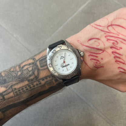 Kappa 2000's Quartz Analog Watch features black leather straps, a silver-tone case, and a white dial. The bezel is marked in five-minute increments from 5 to 55. The dial has a Kappa logo at the top and Kappa text below the center. The hour markers are represented by white dots and numerals. The watch has a stainless steel case back and is marked as a limited edition model.