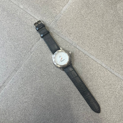 Kappa 2000's Quartz Analog Watch features black leather straps, a silver-tone case, and a white dial. The bezel is marked in five-minute increments from 5 to 55. The dial has a Kappa logo at the top and Kappa text below the center. The hour markers are represented by white dots and numerals. The watch has a stainless steel case back and is marked as a limited edition model.