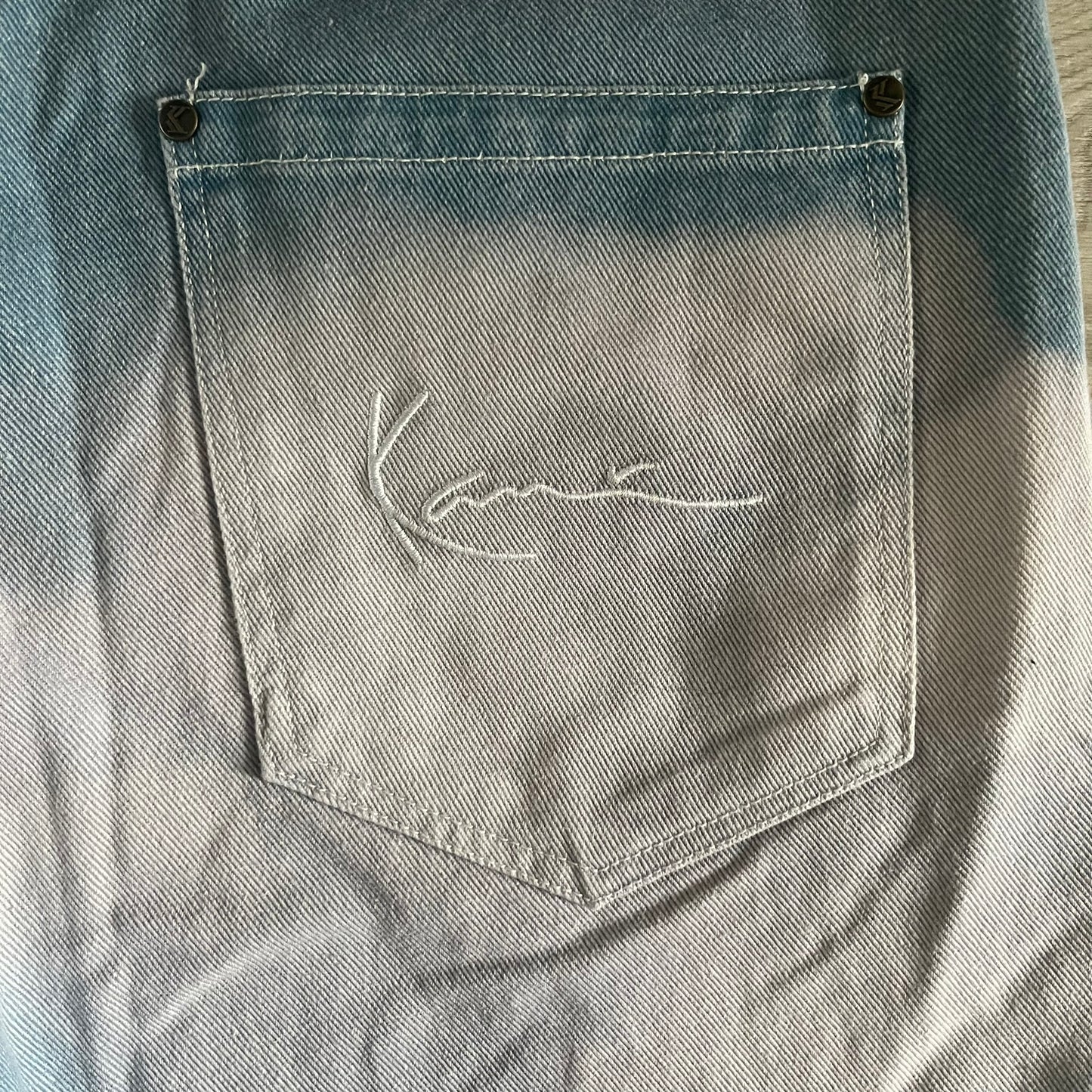 The Karl Kani Signature Eagle Printed Jeans feature a multi-tone eagle graphic over a mountain landscape on a classic blue denim base. Made from 100% cotton, these baggy jeans have a relaxed, wide-leg fit with straight cut legs, a button and zip fastening, and embroidered Karl Kani branding on the back and front pockets. The all-over print extends across the front and back, creating a unique and vintage-inspired look from the FW22 Season.