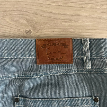 The Karl Kani Signature Eagle Printed Jeans feature a multi-tone eagle graphic over a mountain landscape on a classic blue denim base. Made from 100% cotton, these baggy jeans have a relaxed, wide-leg fit with straight cut legs, a button and zip fastening, and embroidered Karl Kani branding on the back and front pockets. The all-over print extends across the front and back, creating a unique and vintage-inspired look from the FW22 Season.