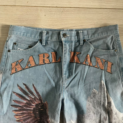 The Karl Kani Signature Eagle Printed Jeans feature a multi-tone eagle graphic over a mountain landscape on a classic blue denim base. Made from 100% cotton, these baggy jeans have a relaxed, wide-leg fit with straight cut legs, a button and zip fastening, and embroidered Karl Kani branding on the back and front pockets. The all-over print extends across the front and back, creating a unique and vintage-inspired look from the FW22 Season.