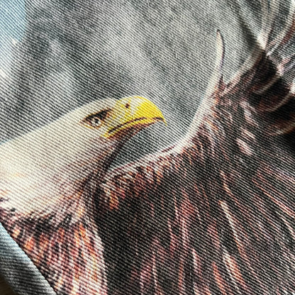 The Karl Kani Signature Eagle Printed Jeans feature a multi-tone eagle graphic over a mountain landscape on a classic blue denim base. Made from 100% cotton, these baggy jeans have a relaxed, wide-leg fit with straight cut legs, a button and zip fastening, and embroidered Karl Kani branding on the back and front pockets. The all-over print extends across the front and back, creating a unique and vintage-inspired look from the FW22 Season.