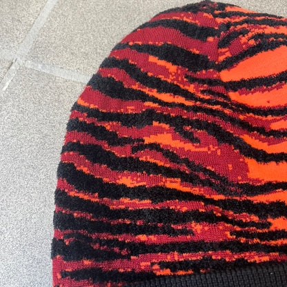 Kenzo x H&amp;M Orange Tiger Camo Beanie is a knit beanie from the 2016 collaboration. It features an all-over tiger camouflage pattern in red, orange, and dark red tones, woven directly into the fabric. The design is finished with a black cuff and can be worn either slouched or folded for a more traditional beanie fit.