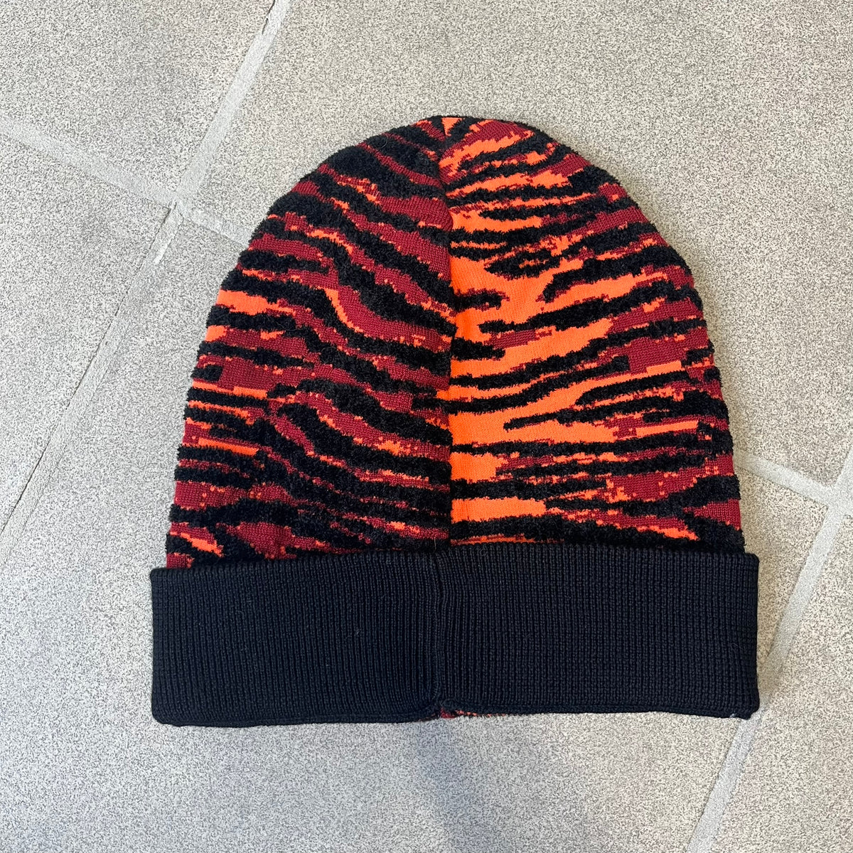 Kenzo x H&amp;M Orange Tiger Camo Beanie is a knit beanie from the 2016 collaboration. It features an all-over tiger camouflage pattern in red, orange, and dark red tones, woven directly into the fabric. The design is finished with a black cuff and can be worn either slouched or folded for a more traditional beanie fit.