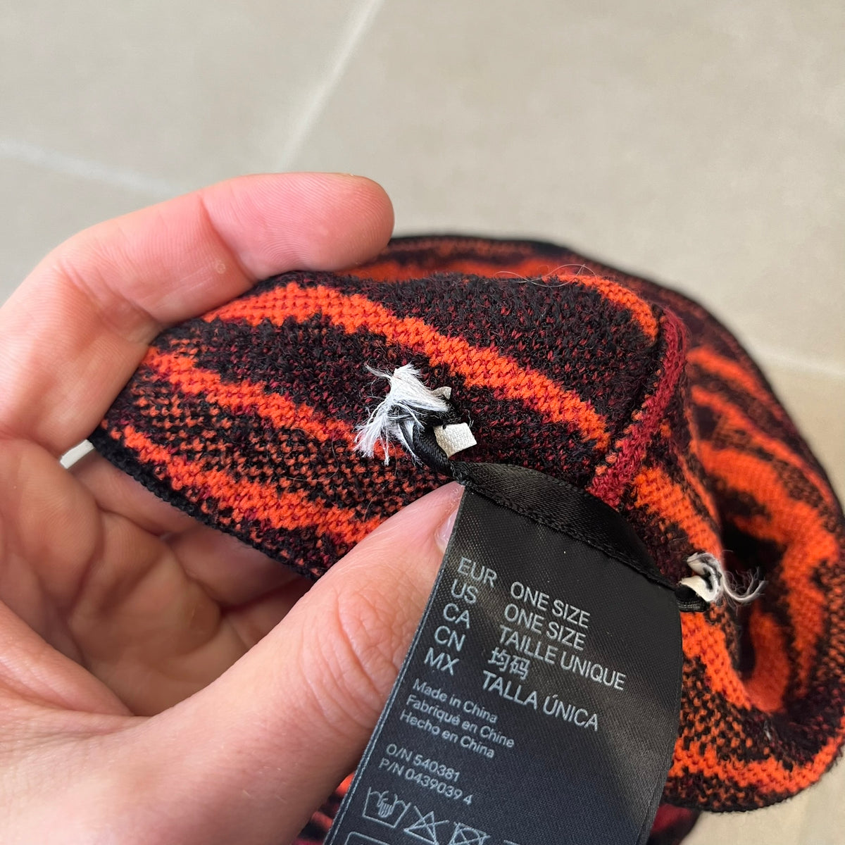 Kenzo x H&amp;M Orange Tiger Camo Beanie is a knit beanie from the 2016 collaboration. It features an all-over tiger camouflage pattern in red, orange, and dark red tones, woven directly into the fabric. The design is finished with a black cuff and can be worn either slouched or folded for a more traditional beanie fit.