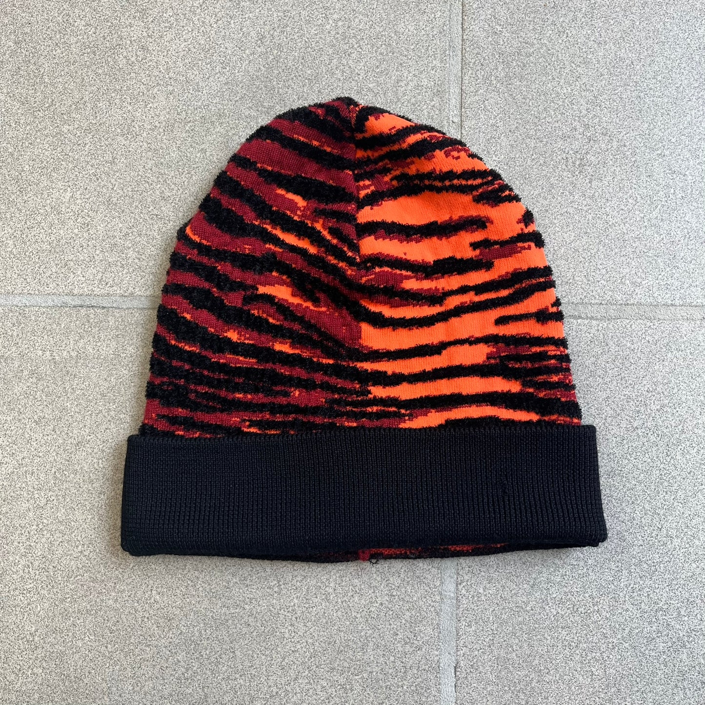 Kenzo x H&amp;M Orange Tiger Camo Beanie is a knit beanie from the 2016 collaboration. It features an all-over tiger camouflage pattern in red, orange, and dark red tones, woven directly into the fabric. The design is finished with a black cuff and can be worn either slouched or folded for a more traditional beanie fit.