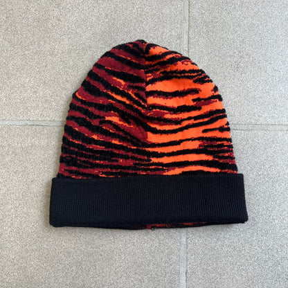 Kenzo x H&amp;M Orange Tiger Camo Beanie is a knit beanie from the 2016 collaboration. It features an all-over tiger camouflage pattern in red, orange, and dark red tones, woven directly into the fabric. The design is finished with a black cuff and can be worn either slouched or folded for a more traditional beanie fit.