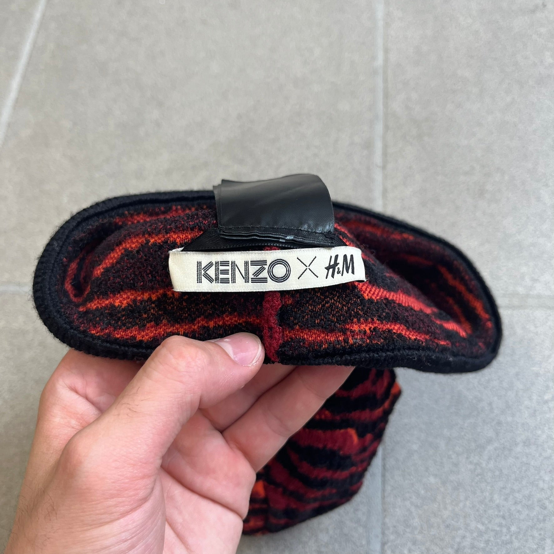 Kenzo x H&amp;M Orange Tiger Camo Beanie is a knit beanie from the 2016 collaboration. It features an all-over tiger camouflage pattern in red, orange, and dark red tones, woven directly into the fabric. The design is finished with a black cuff and can be worn either slouched or folded for a more traditional beanie fit.