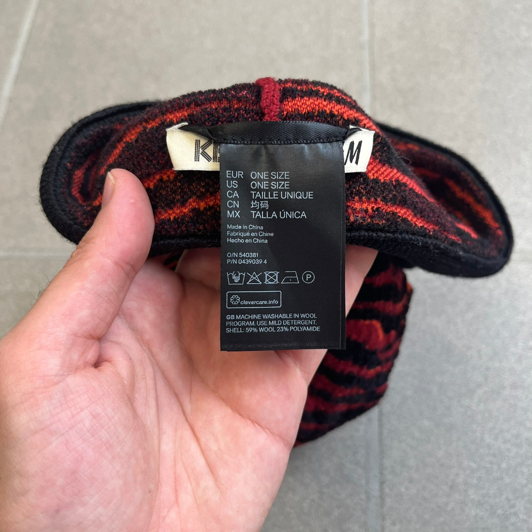 Kenzo x H&amp;M Orange Tiger Camo Beanie is a knit beanie from the 2016 collaboration. It features an all-over tiger camouflage pattern in red, orange, and dark red tones, woven directly into the fabric. The design is finished with a black cuff and can be worn either slouched or folded for a more traditional beanie fit.