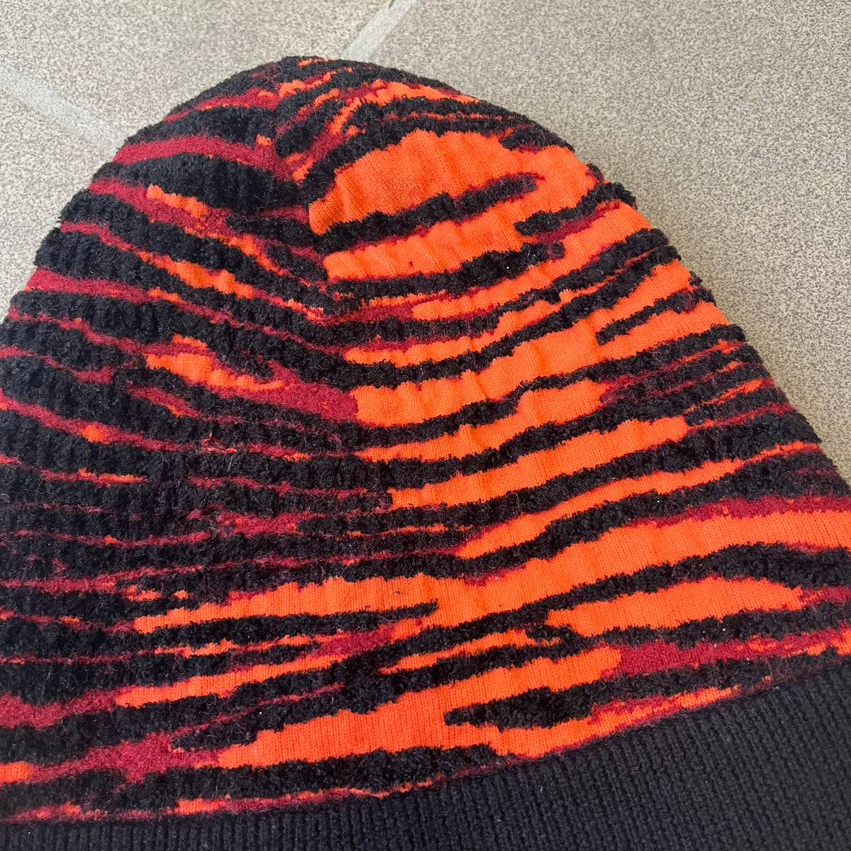 Kenzo x H&amp;M Orange Tiger Camo Beanie is a knit beanie from the 2016 collaboration. It features an all-over tiger camouflage pattern in red, orange, and dark red tones, woven directly into the fabric. This second version of the beanie is tighter and thicker, so the black cuff can't be folded.