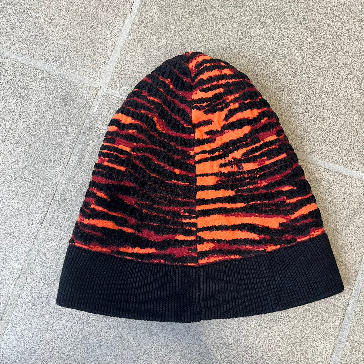 Kenzo x H&amp;M Orange Tiger Camo Beanie is a knit beanie from the 2016 collaboration. It features an all-over tiger camouflage pattern in red, orange, and dark red tones, woven directly into the fabric. This second version of the beanie is tighter and thicker, so the black cuff can't be folded.