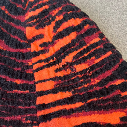 Kenzo x H&amp;M Orange Tiger Camo Beanie is a knit beanie from the 2016 collaboration. It features an all-over tiger camouflage pattern in red, orange, and dark red tones, woven directly into the fabric. This second version of the beanie is tighter and thicker, so the black cuff can't be folded.