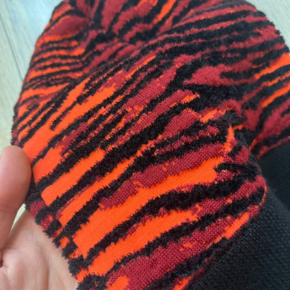 Kenzo x H&amp;M Orange Tiger Camo Beanie is a knit beanie from the 2016 collaboration. It features an all-over tiger camouflage pattern in red, orange, and dark red tones, woven directly into the fabric. The design is finished with a black cuff and can be worn either slouched or folded for a more traditional beanie fit.