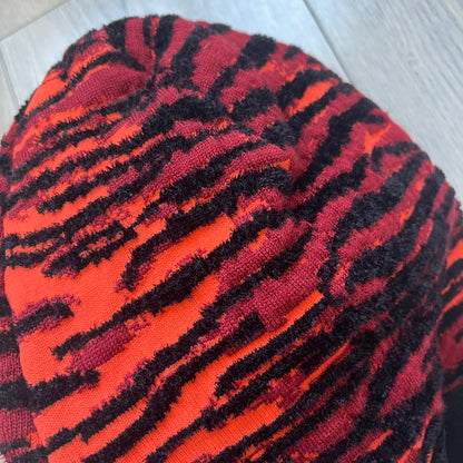 Kenzo x H&amp;M Orange Tiger Camo Beanie is a knit beanie from the 2016 collaboration. It features an all-over tiger camouflage pattern in red, orange, and dark red tones, woven directly into the fabric. The design is finished with a black cuff and can be worn either slouched or folded for a more traditional beanie fit.