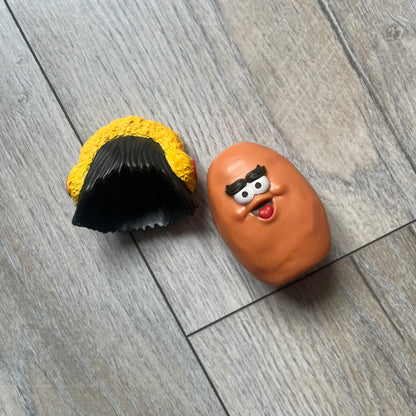 Kerwin Frost x McDonald’s McNugget Figure is a 2023 release from the Kerwin Frost x McDonald’s Nugget Buddies collaboration. The figure combines the Waffutu body with a Darla head, featuring a smiling McNugget character with long hair and yellow earmuffs.