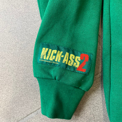 Kick-Ass 2 Full Zip 2013 Promo Hoodie is a green full-zip hoodie with yellow printed lines matching the costume worn by Kick-Ass in Kick-Ass 2. The zipper extends through the hood, allowing it to close into a mask with see-through mesh eye panels. It features a Kick-Ass 2 (2013) Universal Studios licensed neck tag, a matching movie logo patch on the sleeve, and is made in the USA.
