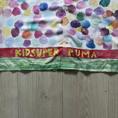 From the KidSuper Studios x Puma 2020 collection, this reversible football shirt (598953-02) showcases a watercolor-style all-over crowd print with vibrant color detailing. The design includes a red and yellow co-branded banner, a green field stripe and a back graphic of a football player doing a bicycle kick. Complete with a chest pocket and embroidered KidSuper Studios x Puma logo.