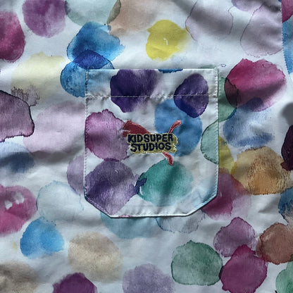 From the KidSuper Studios x Puma 2020 collection, this reversible football shirt (598953-02) showcases a watercolor-style all-over crowd print with vibrant color detailing. The design includes a red and yellow co-branded banner, a green field stripe and a back graphic of a football player doing a bicycle kick. Complete with a chest pocket and embroidered KidSuper Studios x Puma logo.