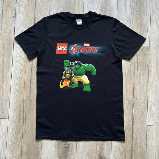 LEGO Avengers 2016 Promo Tee is a black T-shirt featuring a LEGO Marvel Avengers logo on the front. Below the logo is a graphic of LEGO Hulk holding Loki upside down. The shirt is made on a Gildan blank and includes 2016 LEGO and Marvel licensing inside the shirt.