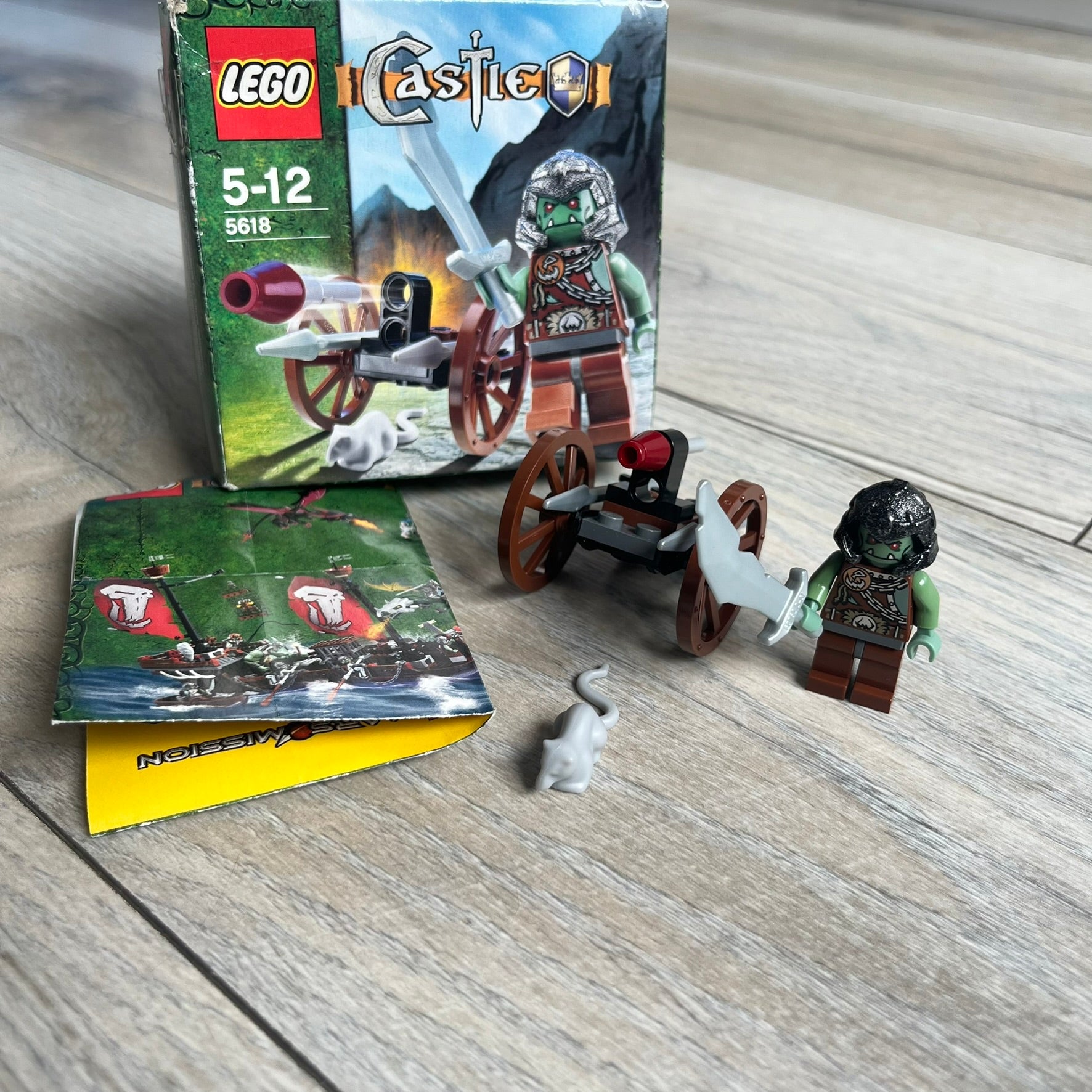 LEGO Castle 5618 Troll Warrior Set is a 2008 release consisting of 19 pieces. The set includes a Troll Warrior minifigure, a light grey rat, and a small attack cart built with two wheels, a baseplate, two silver spears, and a flick-fire missile with a maroon tip. The set was part of the 2008 Castle theme where trolls are depicted attacking the Crown Kingdom.
