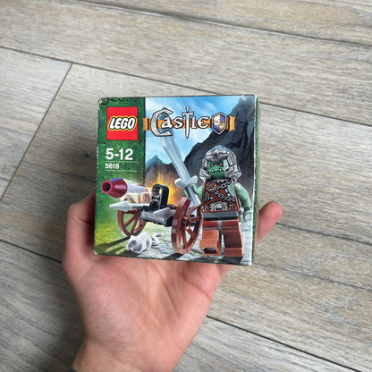 LEGO Castle 5618 Troll Warrior Set is a 2008 release consisting of 19 pieces. The set includes a Troll Warrior minifigure, a light grey rat, and a small attack cart built with two wheels, a baseplate, two silver spears, and a flick-fire missile with a maroon tip. The set was part of the 2008 Castle theme where trolls are depicted attacking the Crown Kingdom.
