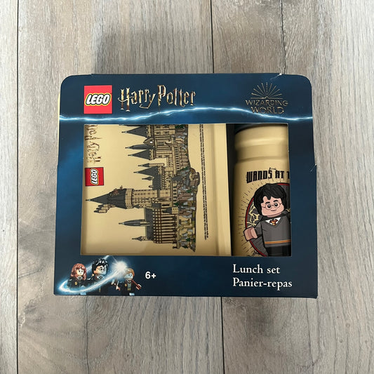 LEGO Harry Potter 2023 Hogwarts Lunch Set is a beige-themed lunch set designed for children aged 3 and up. It includes a polypropylene lunch box and a 390 mL drinking bottle with a silicone spout and hygiene cap. Both items feature illustrations of LEGO Harry Potter characters. The lunch box has easy-open clips, a movable internal divider for separating food, and a lid that can also be used as a plate. The set is designed for portability and everyday use.