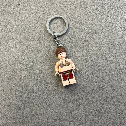 LEGO Star Wars 851938 Princess Leia Key Chain is a 2007 LEGO Gear accessory featuring a Princess Leia minifigure attached to a metal key ring and chain. The figure is permanently fixed to the chain and cannot be removed. The minifigure depicts Princess Leia in her bikini outfit from Jabba’s sail barge scene in Star Wars: Return of the Jedi.