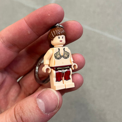 LEGO Star Wars 851938 Princess Leia Key Chain is a 2007 LEGO Gear accessory featuring a Princess Leia minifigure attached to a metal key ring and chain. The figure is permanently fixed to the chain and cannot be removed. The minifigure depicts Princess Leia in her bikini outfit from Jabba’s sail barge scene in Star Wars: Return of the Jedi.