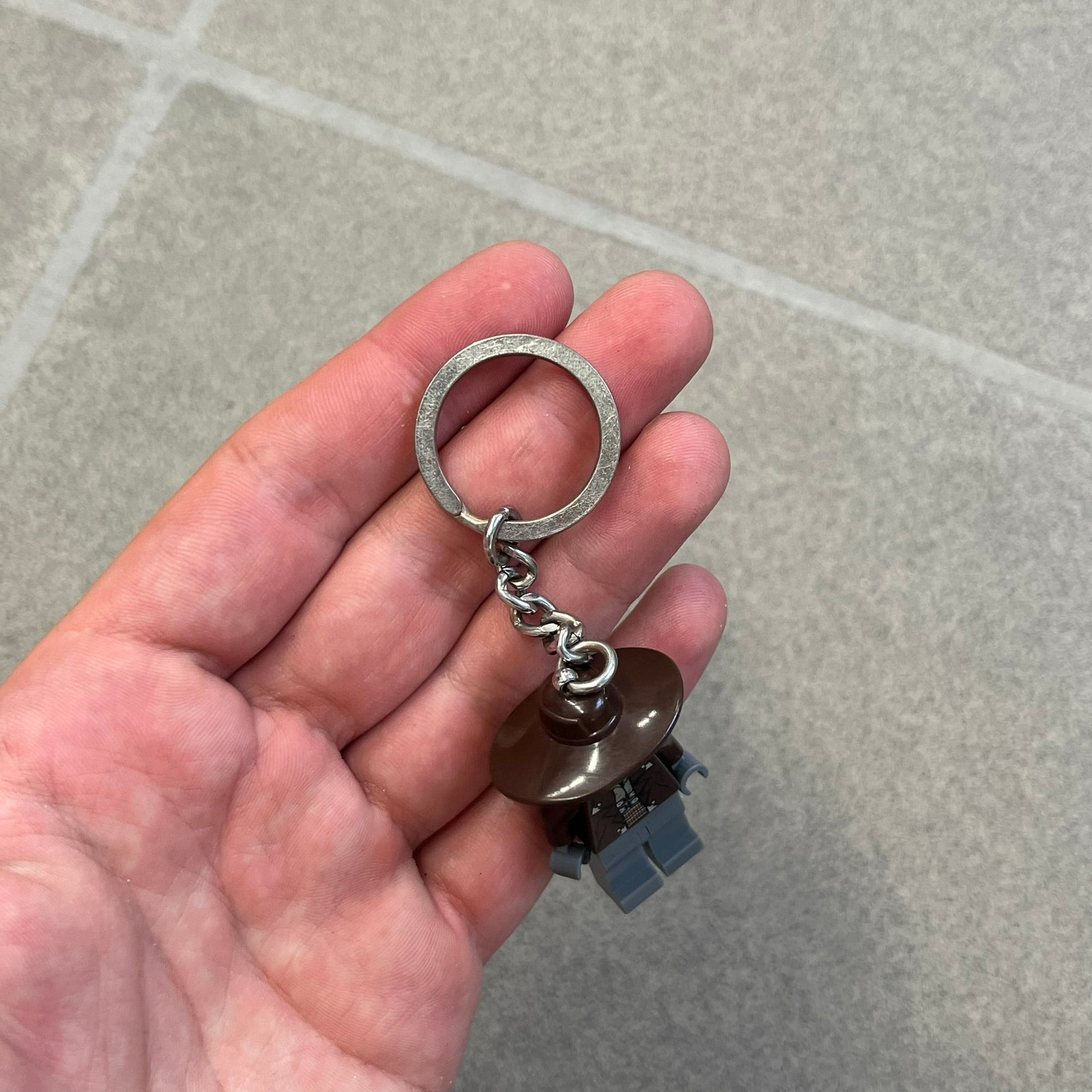LEGO Star Wars 853127 Cad Bane Key Chain is a 2011 LEGO Gear accessory featuring a Cad Bane minifigure attached to a metal key ring and chain. The figure is permanently fixed to the chain and cannot be removed. The design depicts Cad Bane, the Duros bounty hunter from Star Wars: The Clone Wars, including his signature hat and outfit details.