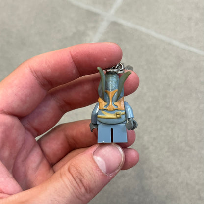 LEGO Star Wars 853413 Watto Key Chain is a 2012 LEGO Gear accessory featuring an authentic LEGO Watto minifigure attached to a metal key ring and chain. The Watto figure is permanently fixed to the chain and cannot be removed. The design represents Watto, the Toydarian junk dealer character from Star Wars: The Phantom Menace.
