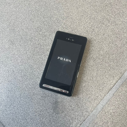 LG Prada KE850 Dummy Phone is a promotional display piece replicating the LG Prada KE850, the world's first capacitive touchscreen phone released through a collaboration between LG and Prada. It features the same black case, silver buttons, and top logo as the original, with a fake screen printed with the Prada logo, matching the real phone's size and design.