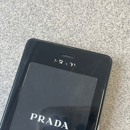 LG Prada KE850 Dummy Phone is a promotional display piece replicating the LG Prada KE850, the world's first capacitive touchscreen phone released through a collaboration between LG and Prada. It features the same black case, silver buttons, and top logo as the original, with a fake screen printed with the Prada logo, matching the real phone's size and design.