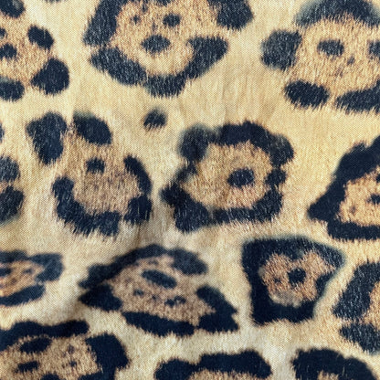 Lacoste x National Geographic AW20 Leopard Polo features an all-over beige, brown and black leopard print pattern across the fabric. The polo has black collar and sleeve hems, with a chest patch featuring the Lacoste crocodile logo in matching pattern colors.